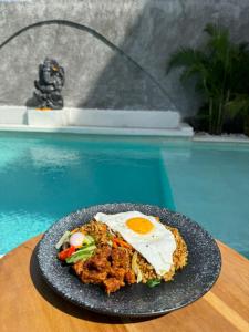 a plate of food on a table next to a pool at Salty Prana Retreat Center in Uluwatu