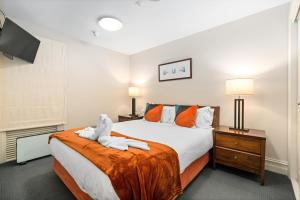 a bedroom with a large bed with orange pillows at THE BEACON - 2 BEDROOM TOWN CENTER APARTMENT 614 in Queenstown