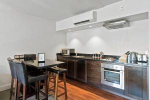 a kitchen with a counter and a table with chairs at Lakeside Living - Modern 2-Bedroom Apartment in Queenstown