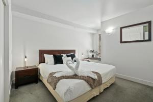two swans sitting on a bed in a bedroom at Lakeside Living - Modern 2-Bedroom Apartment in Queenstown
