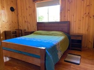 a bedroom with a bed in a wooden room at Vista verde Llonquén in Liquiñe