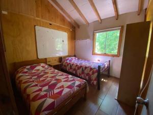 a small room with two beds and a window at Vista verde Llonquén in Liquiñe