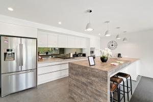 Una cocina con gabinetes blancos y un refrigerador de acero inoxidable. en Alpine Retreat - Panoramic Views, en Queenstown