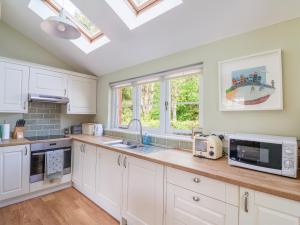a kitchen with white cabinets and a skylight at Questant Lodge in Sidmouth