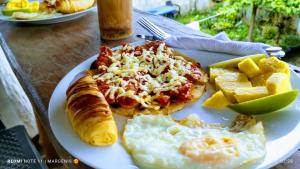 a plate of food with a pizza and eggs and bread at Mi Cabaña El Maderal in Capurganá