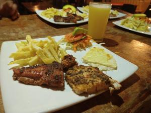 a plate of food with meat and french fries and a drink at Mi Cabaña El Maderal in Capurganá +17 photos