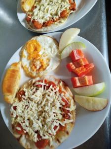dos platos de comida con pizzas y manzanas en una mesa en Mi Cabaña El Maderal en Capurganá