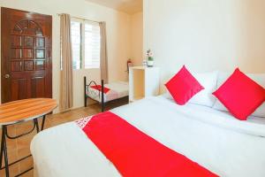 Un dormitorio con una cama con almohadas rojas y una mesa. en Jessa's 5 Guests house en Moalboal