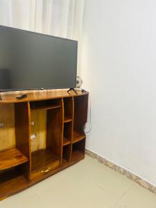 Mini depa de una habitación في بوكالبا: تلفزيون بشاشة مسطحة جالس فوق مركز ترفيهي خشبي