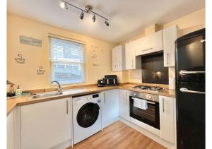 ブリクサムにある1 Captain's Rest Modern 2 bedroom Brixham harbour flatのキッチン(白いキャビネット、洗濯機、乾燥機付)