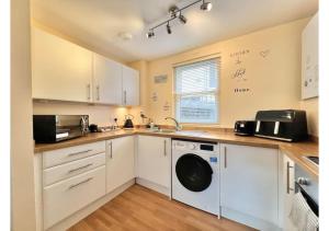 ブリクサムにある1 Captain's Rest Modern 2 bedroom Brixham harbour flatのキッチン(白いキャビネット、洗濯機、乾燥機付)