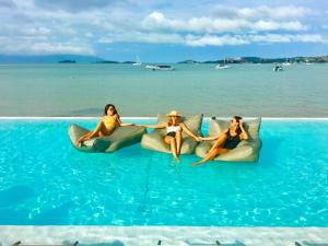 three women are sitting on pillows in the water at Chi Samui Resort in Bophut