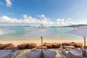 a beach with chairs and umbrellas on the sand at Chi Samui Resort in Bophut