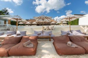 a beach with couches and umbrellas in the sand at Chi Samui Resort in Bophut