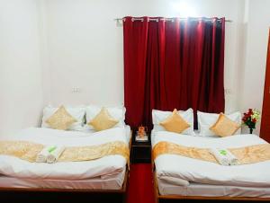 two beds in a room with a red curtain at Hotel Prakriti Darshan in Bhatwāri