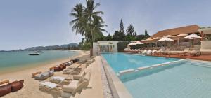 a swimming pool with lounge chairs and a beach at Chi Samui Resort in Bophut