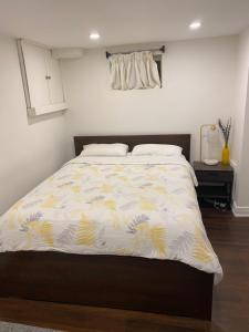 a bedroom with a bed with a yellow and white comforter at Beautiful Lower level 2 bedroom aprt in Toronto