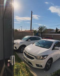 dos autos blancos estacionados en un estacionamiento en Pousada e Espaco AURORA Peruibe en Peruíbe