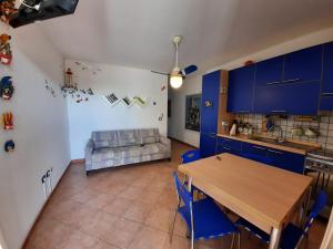 cocina y sala de estar con mesa y armarios azules en LaCasaDeiGechiOtranto, en Casamassella 9 fotos más