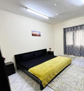 a bedroom with a large bed with a yellow blanket at All in One in Sharjah