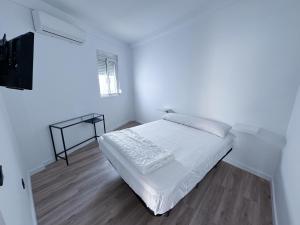 a white bedroom with a bed and a television at Los Alcores 2.0 in Torremolinos