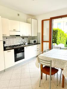 una cucina con mobili bianchi e tavolo di Summer by the sea home a Cavallino-Treporti