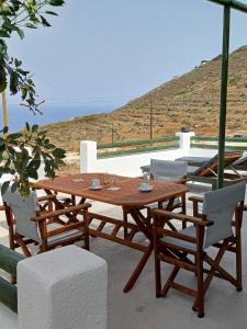 a wooden table and chairs with a view of the ocean at G&O cycladic house with sea view! in Foinikiá