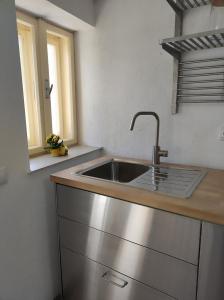 a kitchen with a stainless steel sink and two windows at Casa Via Viscri in Buneşti