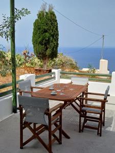 un tavolo e sedie in legno con vista sull'oceano di G&O cycladic house with sea view! a Foinikiá