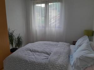 an unmade bed in a bedroom with a window at Lana apartman Pijavice in Jajce