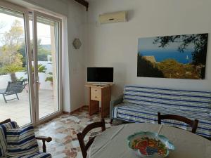 a living room with a table and a couch and a television at La terrazza sul mare - Marina di Novaglie in Alessano
