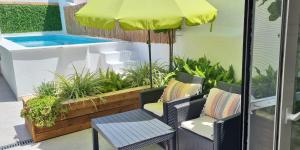 a patio with a swimming pool and two chairs and an umbrella at In Old Town With Pool in Tavira