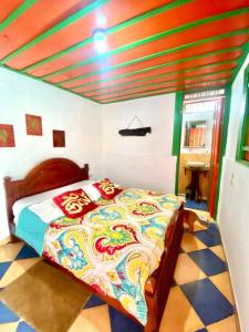 a bedroom with a bed with a colorful comforter at Hostal Estrella de Agua in Salento