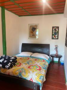 a bedroom with a bed with a colorful blanket at Hostal Estrella de Agua in Salento