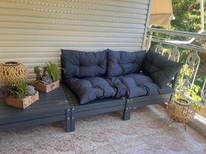 un divano blu seduto su una veranda con due piante in vaso di Alexandra’s apartment a Paralía Akrátas