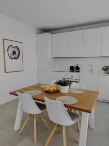 uma cozinha com uma mesa de madeira e cadeiras brancas em Apartment La Mer with Pool em Lido di Jesolo
