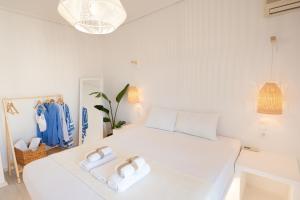 a white bedroom with two white towels on a bed at The White Rose Hotel in Poros