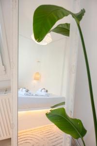 a mirror in a room with a bed and a plant at The White Rose Hotel in Poros