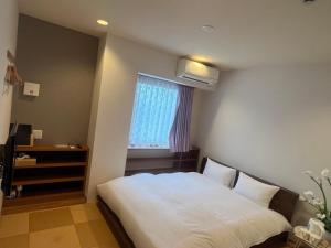 a bedroom with a white bed and a window at Kansai Seaside Hotel in Kaizuka
