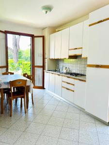 a kitchen with white cabinets and a table with chairs at Beachside Family Garden Retreat in Cavallino-Treporti +10 photos