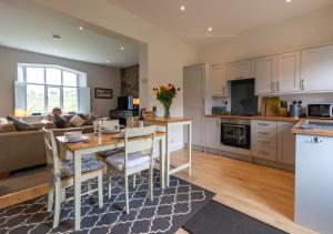 cocina y sala de estar con mesa y sofá en 2 Railway Cottages en Selside