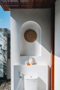 a bathroom with a toilet in a white wall at Suga Estate - Rice Field View Villas in Ubud