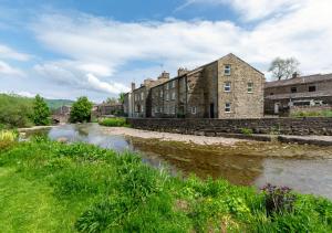 an old stone building next to a river at Hillyard in Hawes
