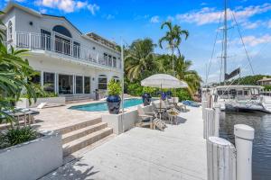 a large white house with a swimming pool and a boat at Villa on Intracoastal Beach in proximity Waterfront Views Access Fogg Key VlLLAS in Fort Lauderdale