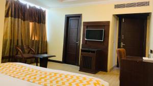 um quarto de hotel com uma cama e uma televisão de ecrã plano em Hotel perial Inn - Nehru Palace em Nova Deli