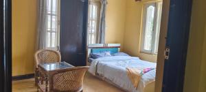 Schlafzimmer mit einem Bett, einem Stuhl und Fenstern in der Unterkunft Bodhi Homestay in Kathmandu
