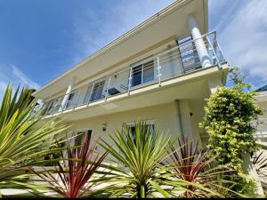 a white house with a balcony and palm trees at Le Vallaya Suites & Spa in Menton