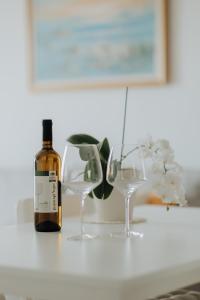 a bottle of wine and two wine glasses on a counter at Mimoza's Sea View Apartment in Paleo Tsifliki