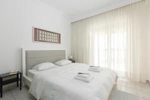 a white bedroom with a bed with two towels on it at Mimoza's Sea View Apartment in Paleo Tsifliki