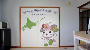 un póster de un gatito de hola con flores en la pared en 東神楽大学ゲストハウス en Higashikagura